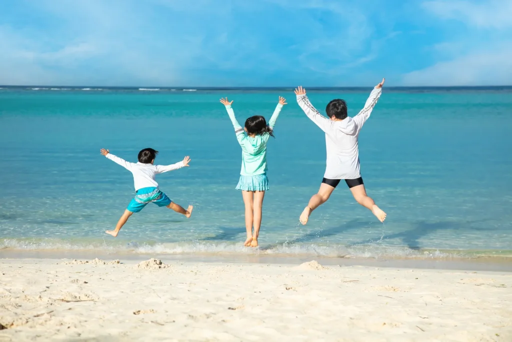 沖縄の海辺でジャンプする3人の子供