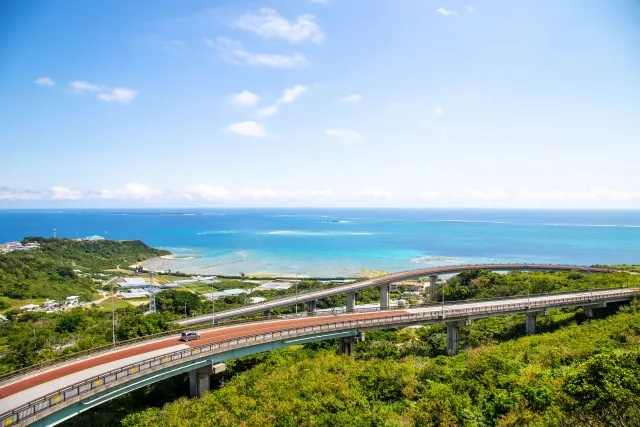 沖縄の海沿いをレンタカーでドライブする様子