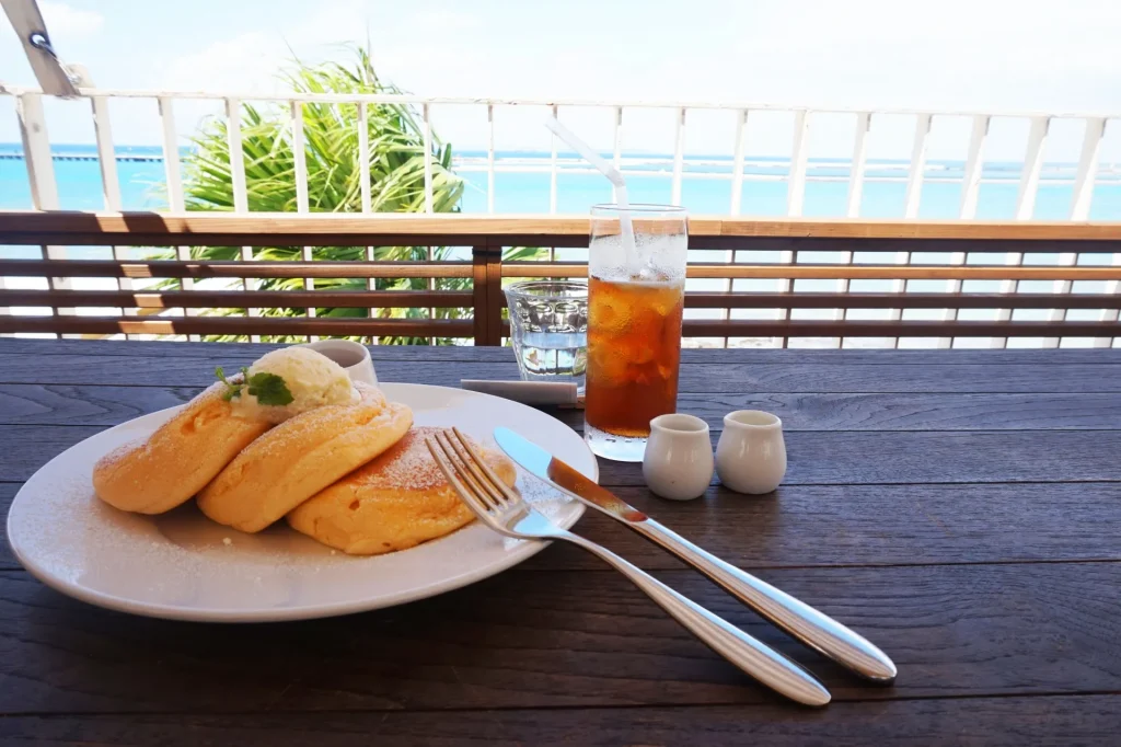 沖縄の海をバックにカフェでパンケーキ