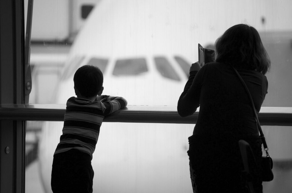 那覇空港の窓から飛行機を眺める子供と親 待ち時間の過ごし方